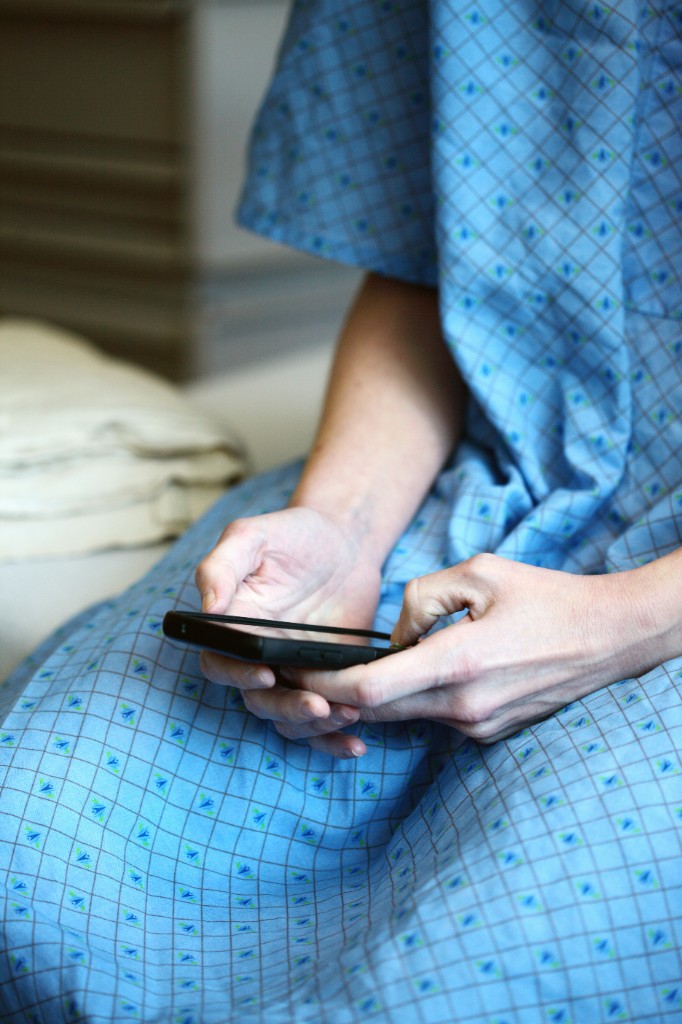 Patient in a hospital gown holding a smartphone