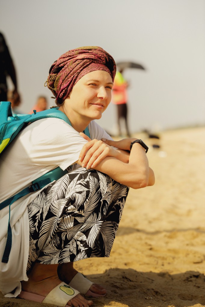 Woman in a colorful headscarf on a beach, smiling