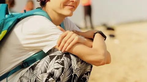 Woman in a colorful headscarf on a beach, smiling